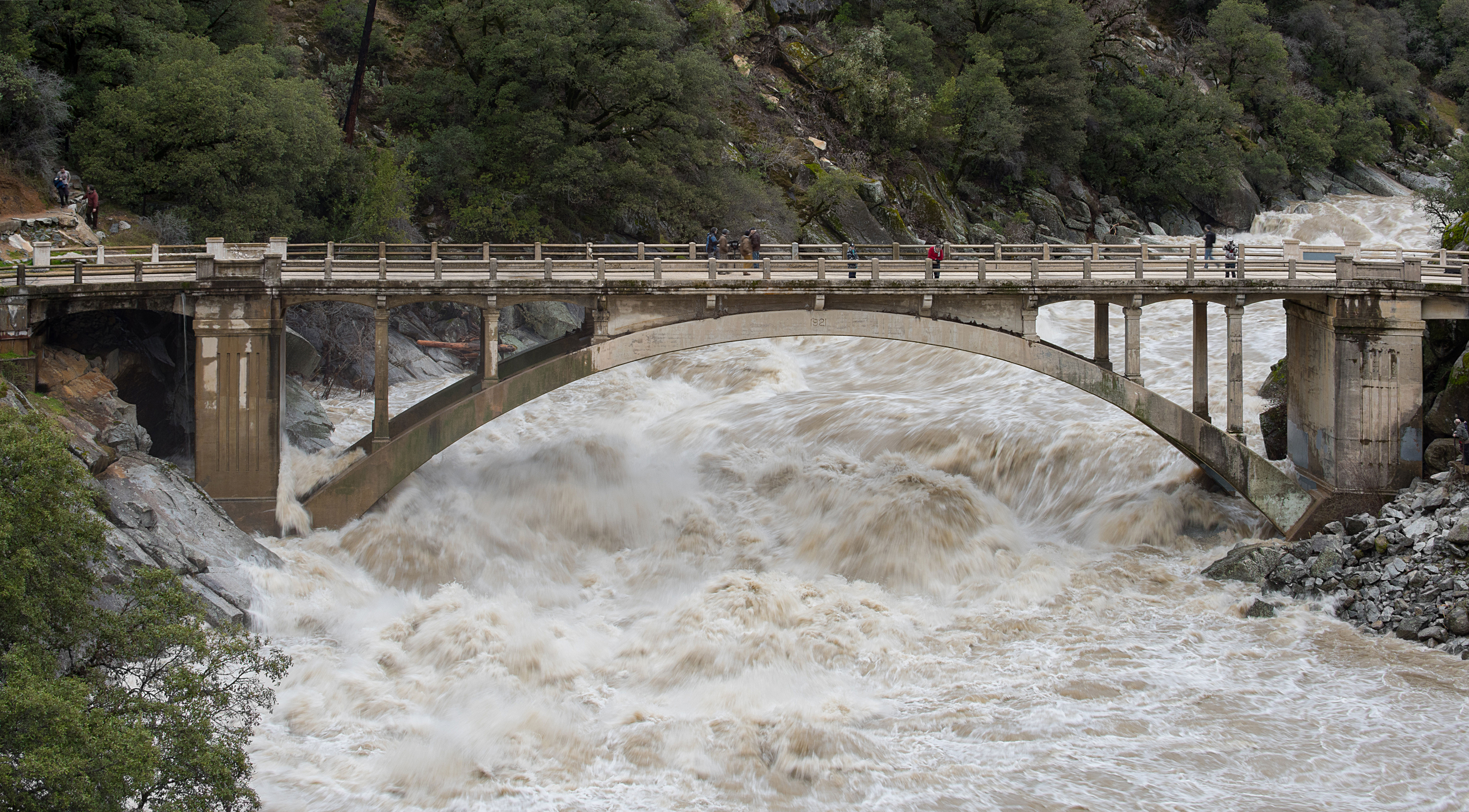 image of flooded river raging under an arched bridge